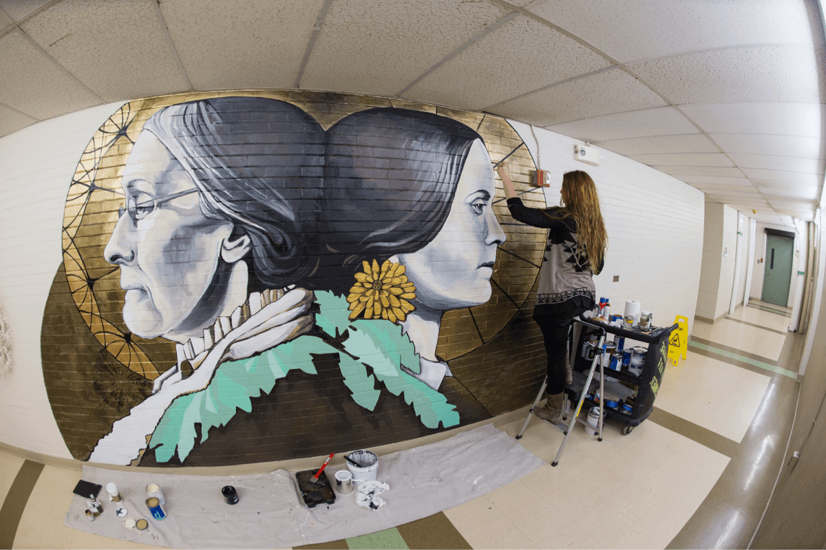 Artist painting a mural at University of Rochester