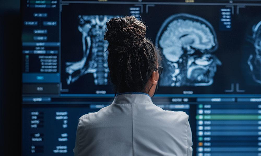 Female Neuroscientist Looking at TV Screen, Analyzing Brain Scan MRI Images, Finding Treatment for Patient. Health Care Neurologist Curing People.