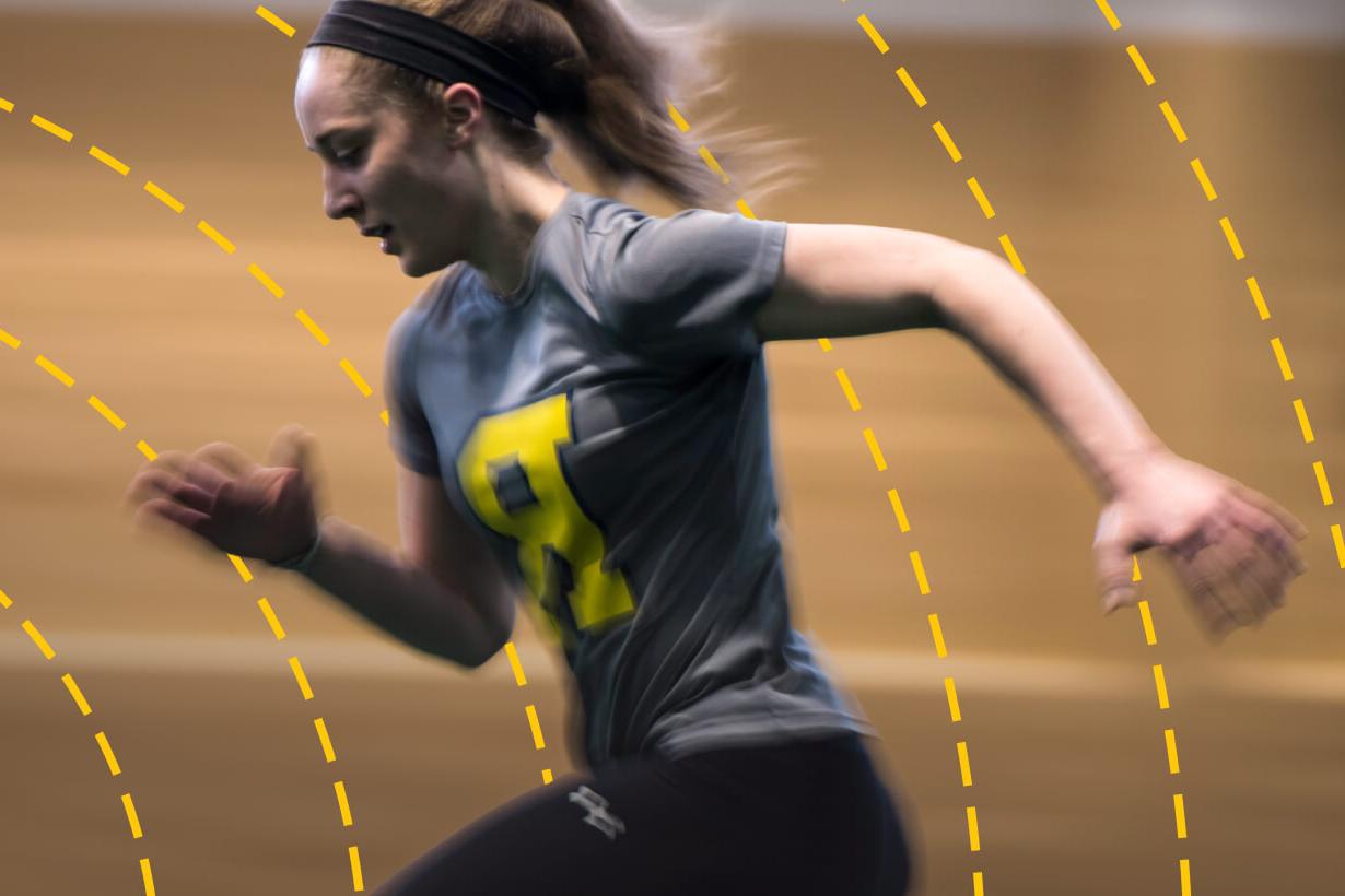 University of Rochester student runs a race on an indoor track.